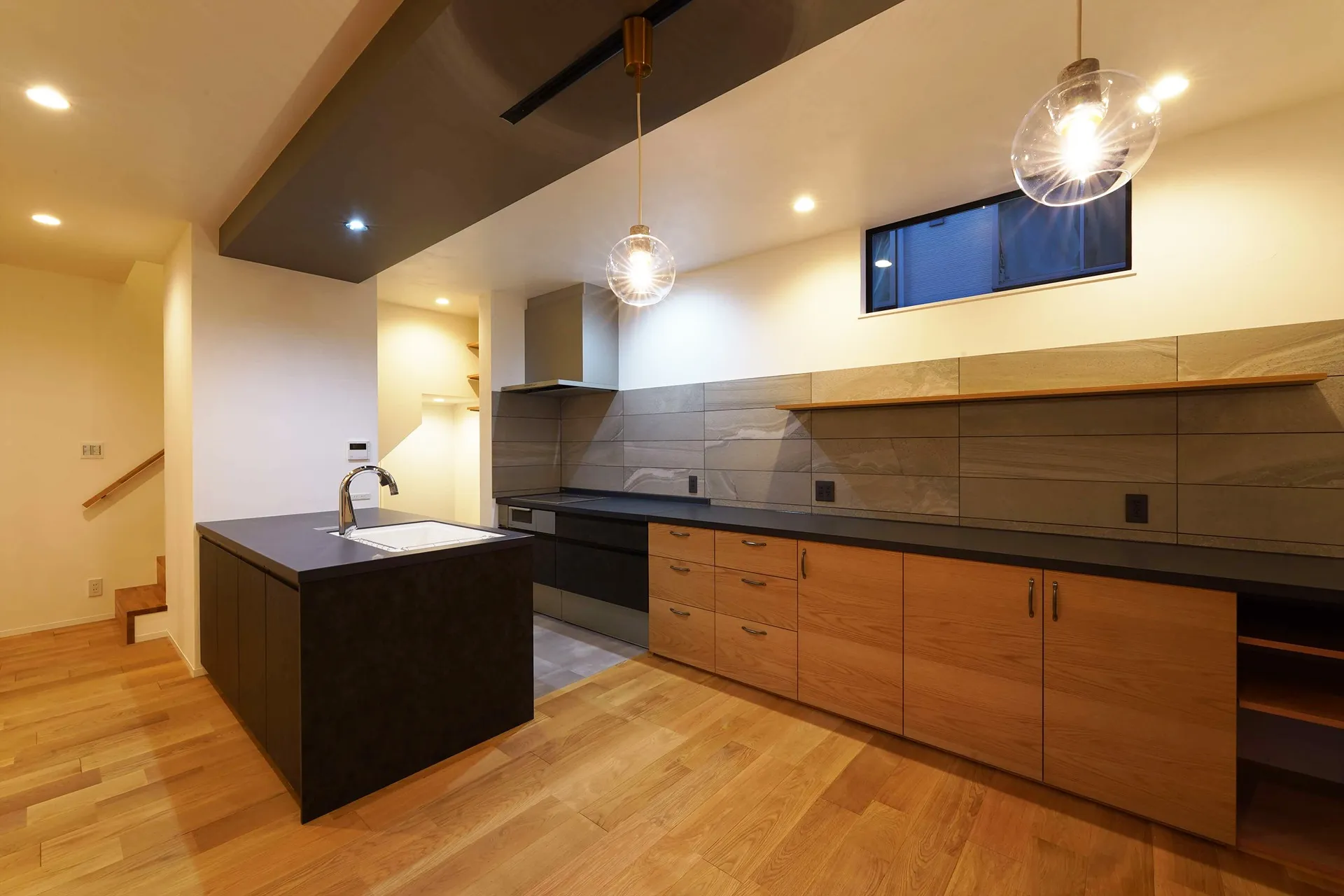 黒の天板とグレーのタイルで上品な格好良さを。扉の木目で柔らかさを演出。