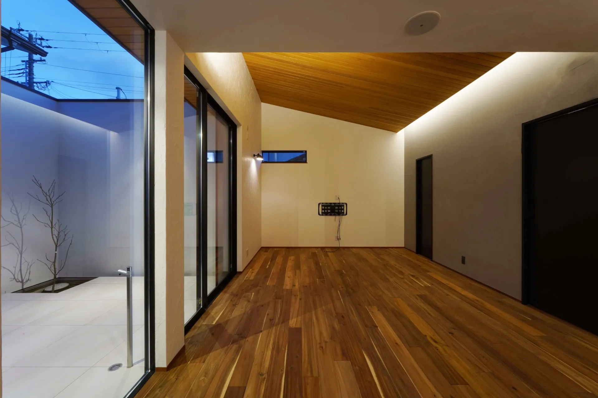 中庭とつながるリビングは勾配天井の板貼りと間接照明で演出。