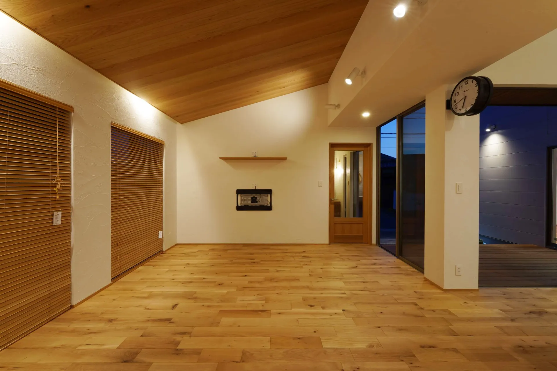 吹抜けのあるダイニングに対しリビングは板貼りの勾配天井に。